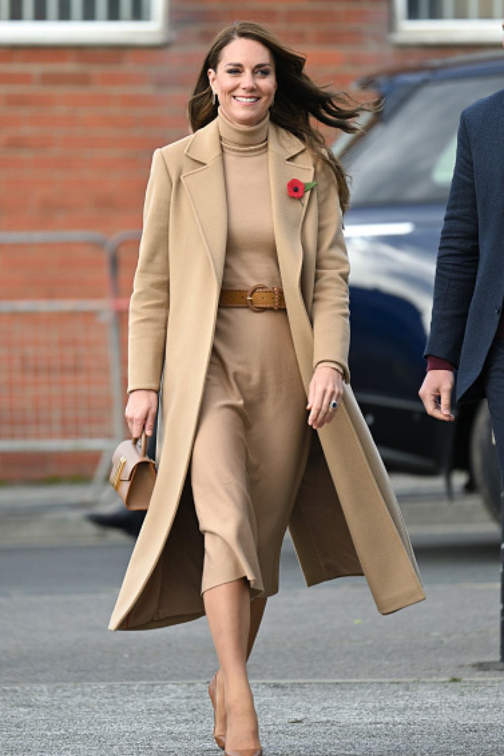 Catherine, Princess of Wales wearing a camel tonal look featuring her regular camel coat over a dress with tan accessories.