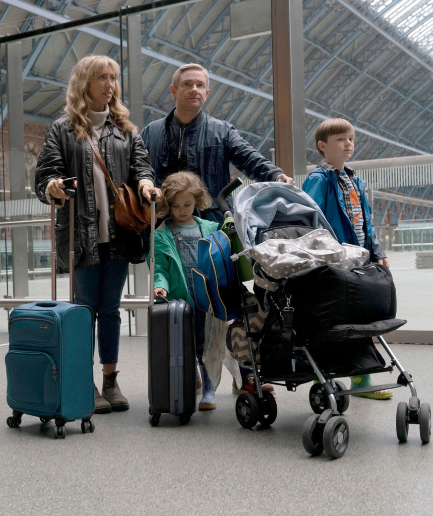 Paul (The Office’s Martin Freeman) and Ally (Daisy Haggard) with luggage and their children standing in a train station all looking stressed.
